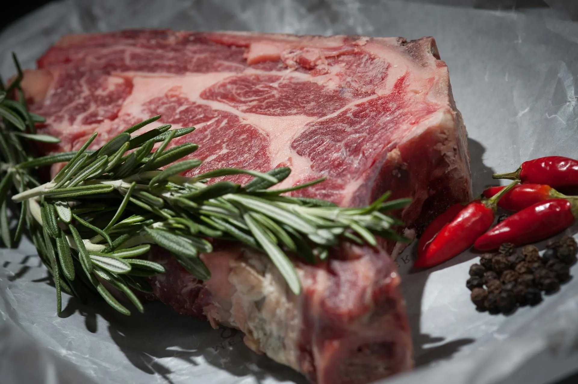 Dry-aged bone-in ribeye steak with rosemary and peppercorns