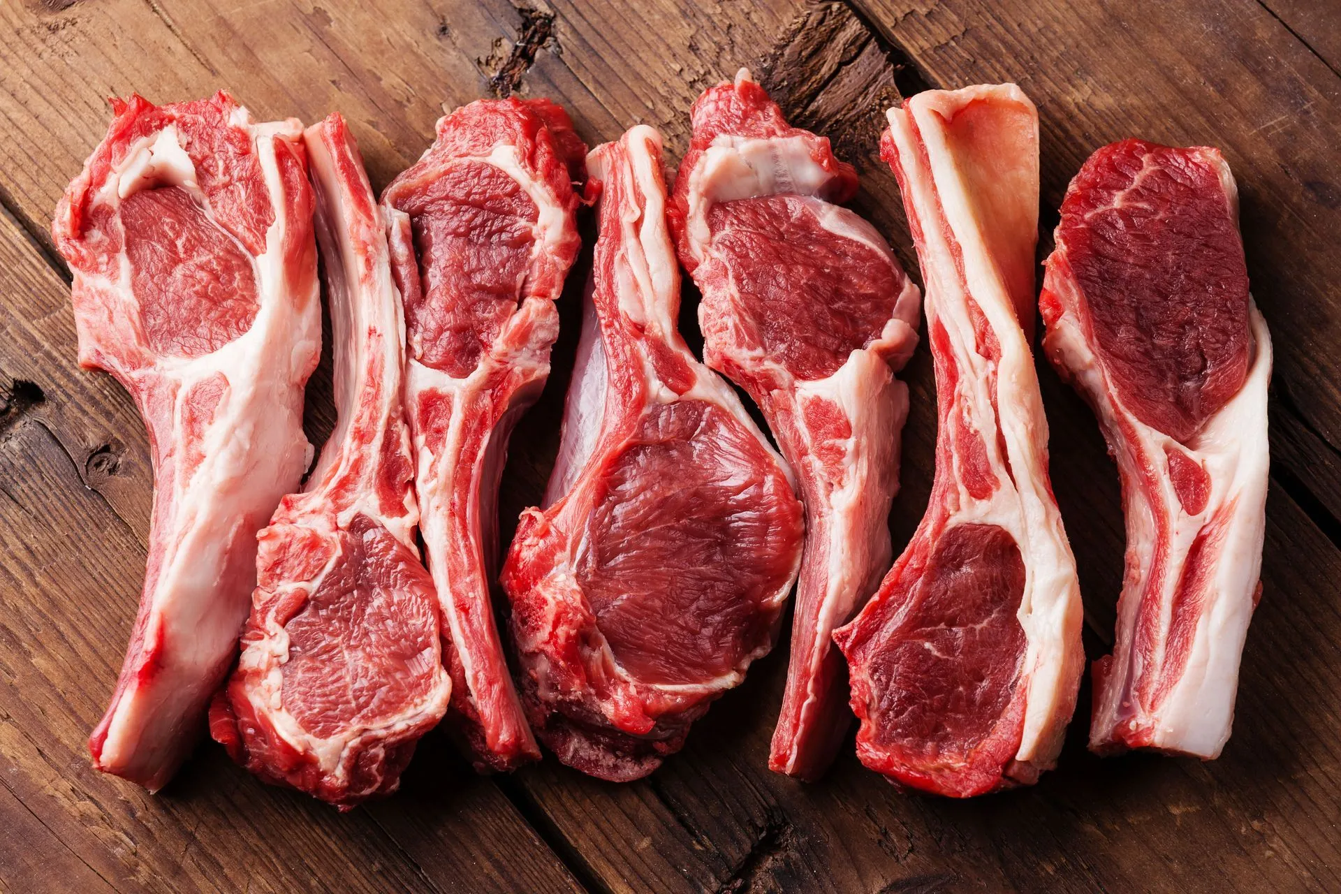 Fresh lamb chops arranged on a rustic wooden board