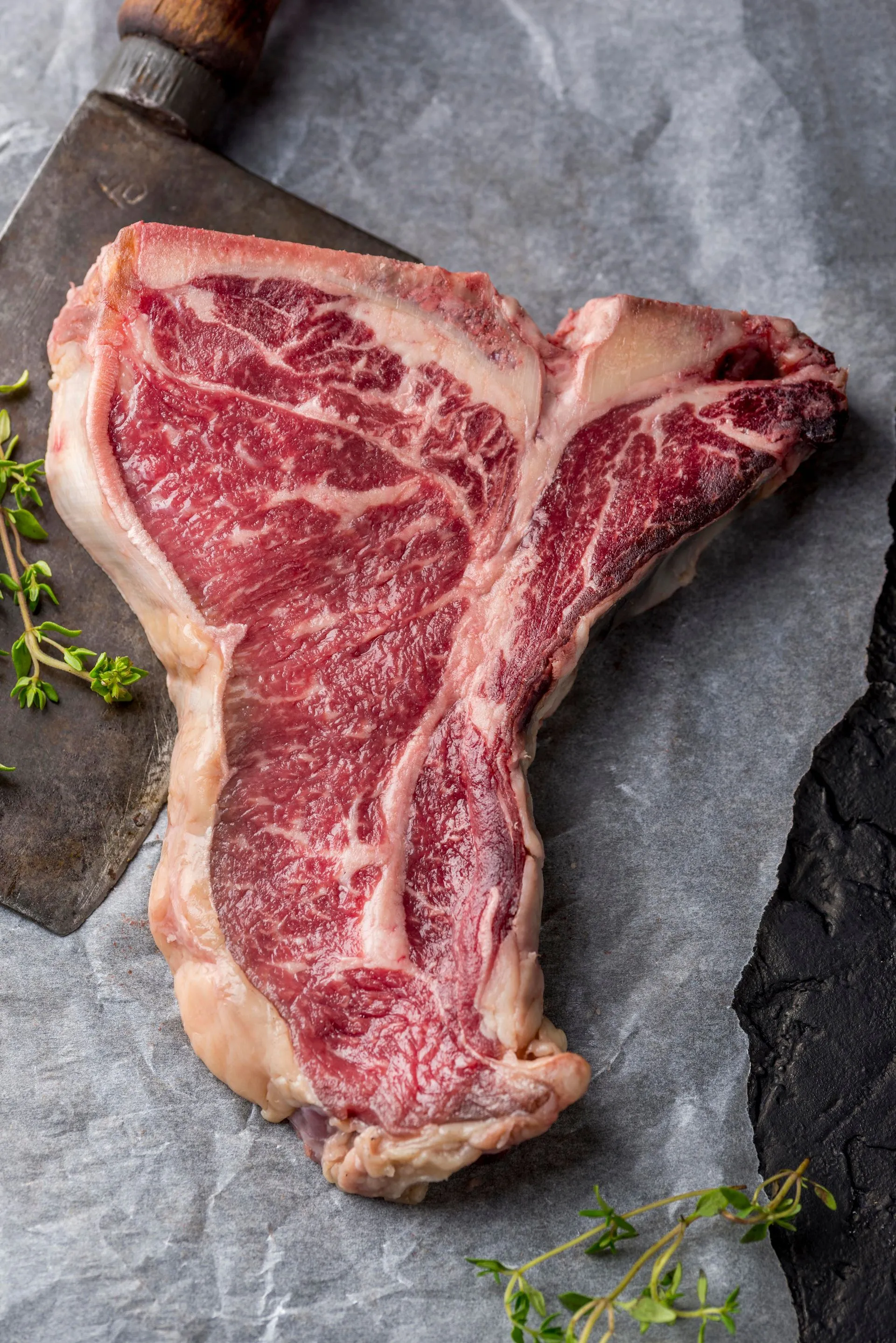 Top view of fresh meat with herbs and cleaver