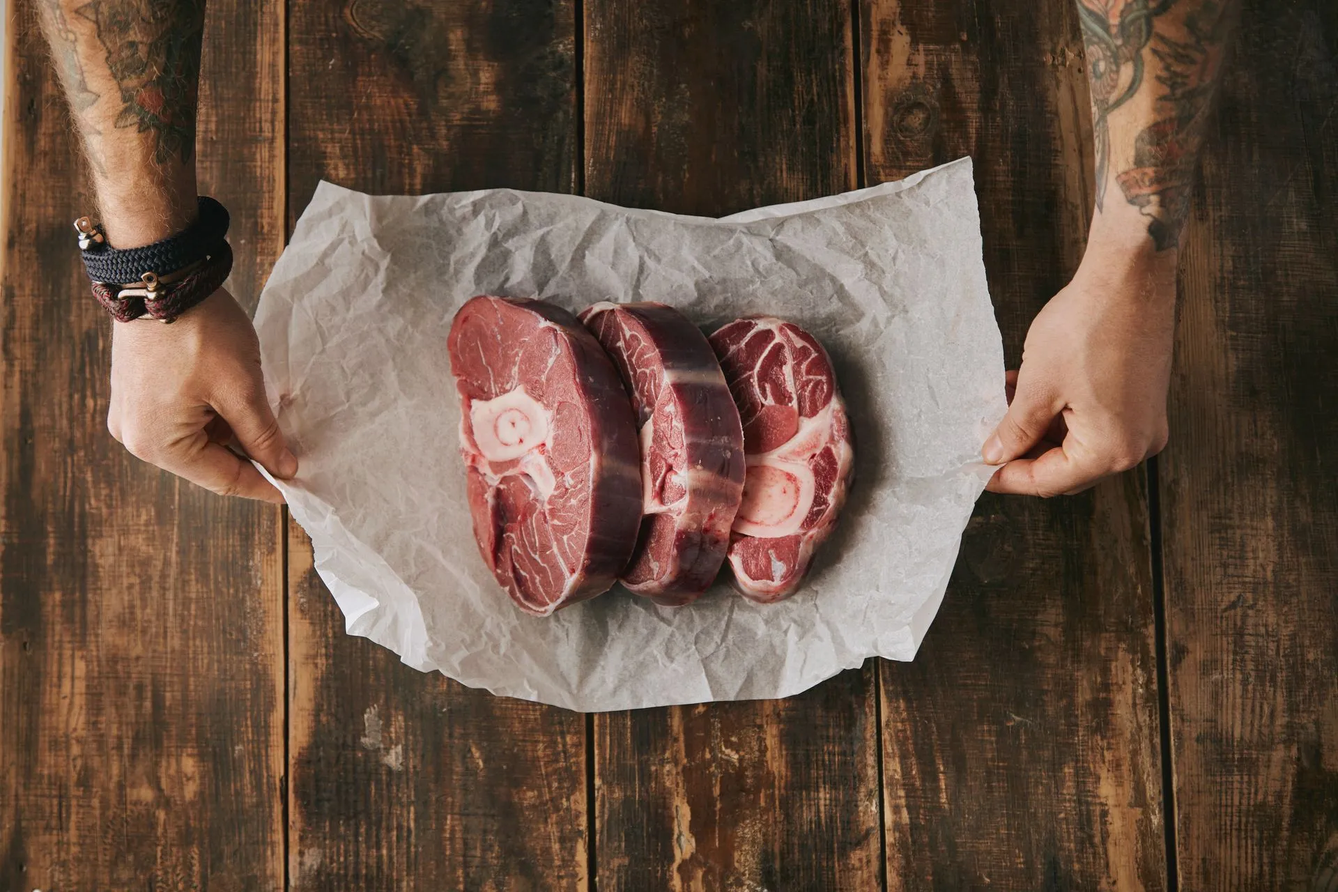 Raw bone-in beef leg steaks on craft paper