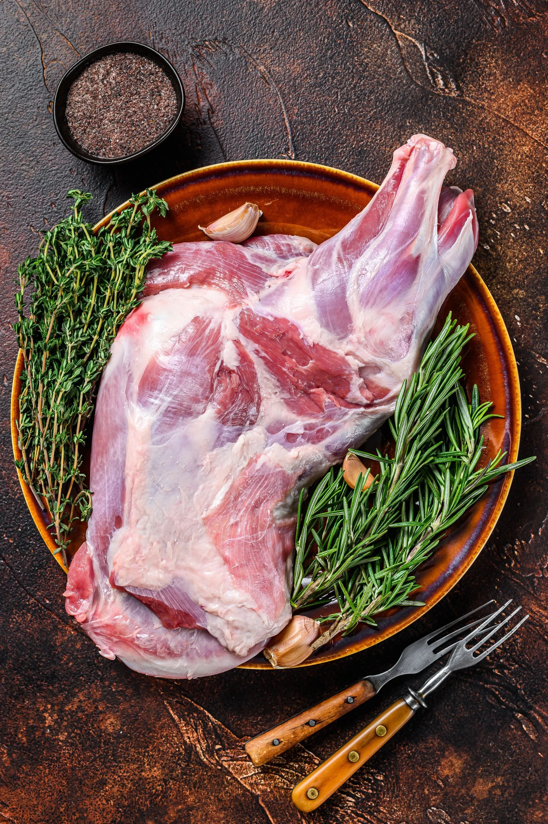 Whole fresh raw lamb shoulder on a plate